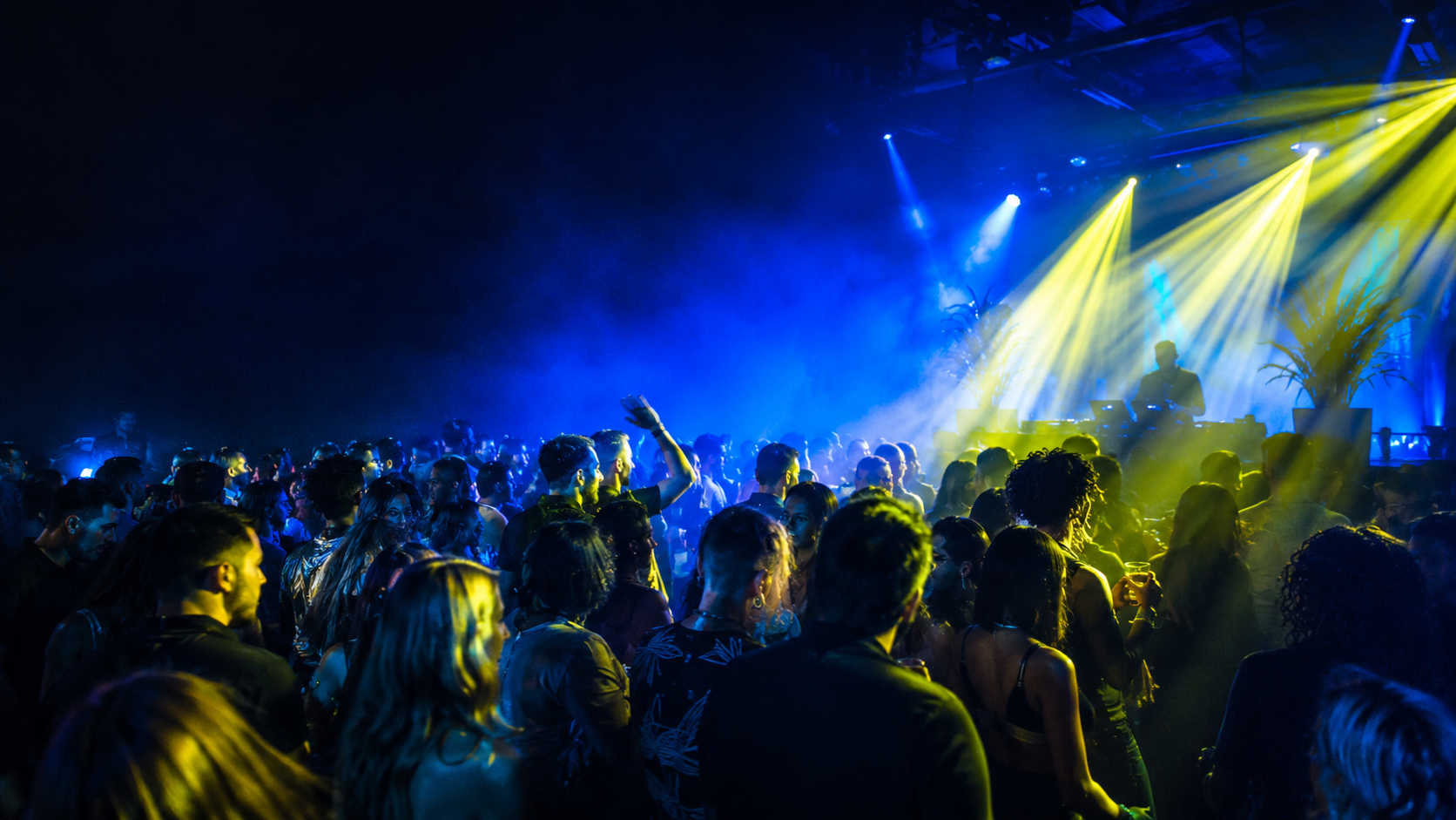 A packed dance floor illuminated by blue and yellow lights